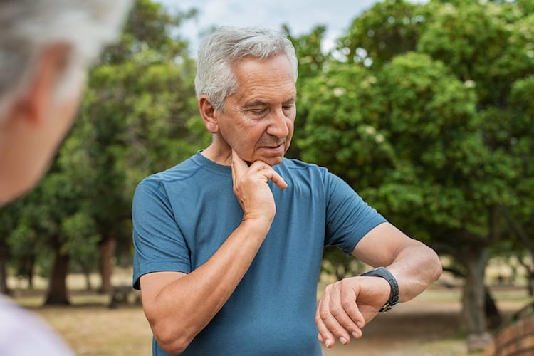 Senior man checking pulse after run.