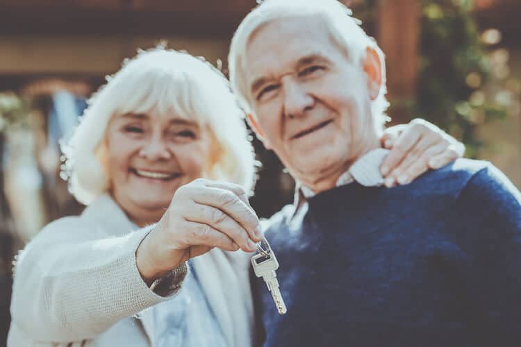 Happy seniors holding keys to their new home.